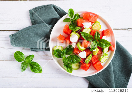 Close up of delicious salad of watermelon, cucumber and ricotta on a plate on the table top view Close up of delicious salad of watermelon, cucumber and ricotta on a plate on the table top view 118626213