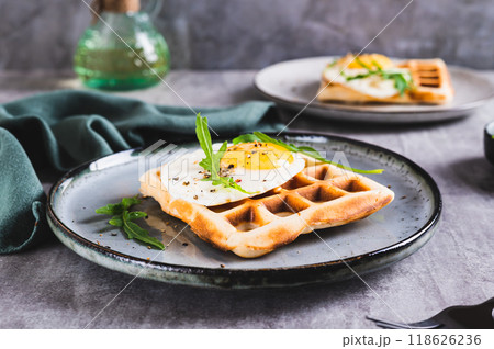 Belgian waffle with fried egg, arugula and spices on a plate on the table 118626236