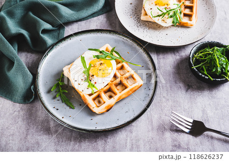 Homemade crispy waffles with egg and arugula on a plate on the table 118626237