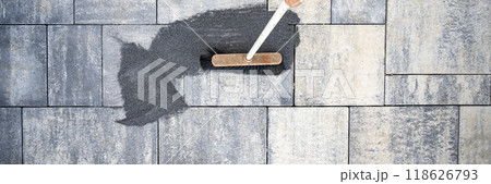 Top view of a broom brushing tile gaps sand in between cement tiles 118626793