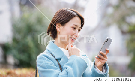スマホを使う女性（冬服・上着・コート） 118628918