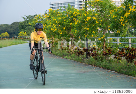 Happiness female cyclist riding a bicycle on bike lane in the park. Cycling is amazing for those looking for a form of cardio or aerobic exercise other than running. 118630090