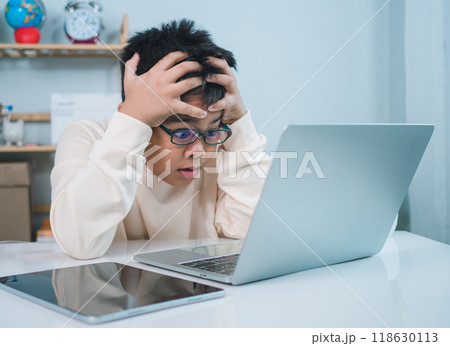 Boy using computer for learning and stressed about online learning, Virtual internet online class from school teacher by remote meeting, Homeschooling and education concept, online education concept. Boy using computer for learning and stressed about online learning, Virtual internet online class from school teacher by remote meeting, Homeschooling and education concept, online education concept. 118630113