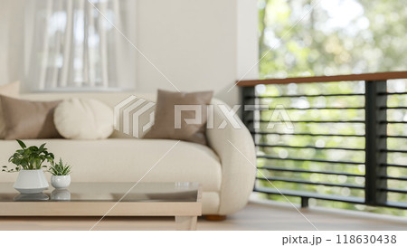 A close-up of a coffee table in a comfortable living room, featuring a modern sofa and a balcony. 118630438