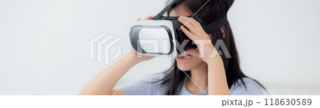Young asian woman wearing vr headset playing game with excited on bed in the bedroom. 118630589