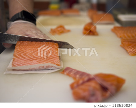 The master chef cuts salmon with a special knife ensuring each piece is uniform. The vibrant color and smooth texture of the salmon are brought to life with every precise slice of salmon. The master chef cuts salmon with a special knife ensuring each piece is uniform. The vibrant color and smooth texture of the salmon are brought to life with every precise slice of salmon. 118630824