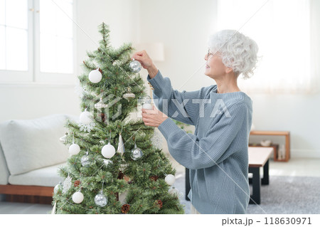 クリスマスツリーに飾り付けをするシニア女性 118630971