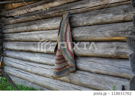 Round, knitted, homemade, old carpet, hanging on the wall of an old log house Round, knitted, homemade, old carpet, hanging on the wall of an old log house 118631762