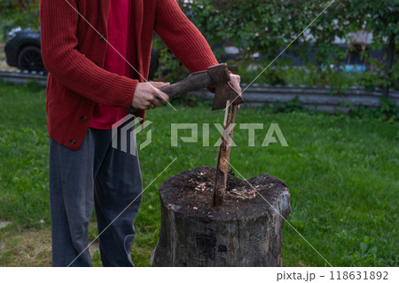 A man is chopping wood for a bonfir A man is chopping small firewood. Evening A man is chopping wood for a bonfir A man is chopping small firewood. Evening 118631892