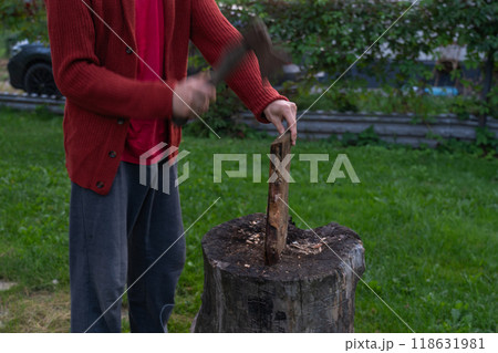 A man is chopping wood for a bonfir A man is chopping small firewood. Evening A man is chopping wood for a bonfir A man is chopping small firewood. Evening 118631981