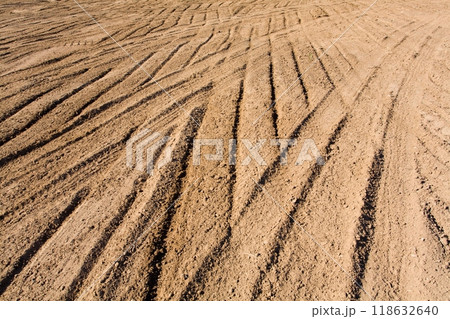 Texture brown yellow clay earth with traces of cars, trucks, tractors. Road with tire tracks. 118632640