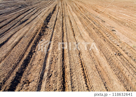 Texture brown yellow clay earth with traces of cars, trucks, tractors. Road with tire tracks. Texture brown yellow clay earth with traces of cars, trucks, tractors. Road with tire tracks. 118632641