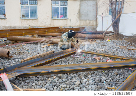Welder in mask welding metal construction on open air. Welder in mask welding metal construction on open air. 118632697