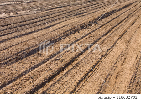 Texture brown yellow clay earth with traces of cars, trucks, tractors. Road with tire tracks. Texture brown yellow clay earth with traces of cars, trucks, tractors. Road with tire tracks. 118632702