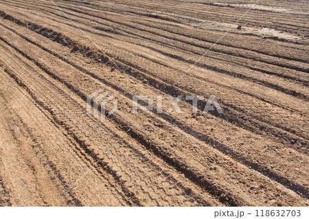 Texture brown yellow clay earth with traces of cars, trucks, tractors. Road with tire tracks. Texture brown yellow clay earth with traces of cars, trucks, tractors. Road with tire tracks. 118632703