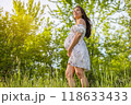 Pregnant woman holding showing belly baby bump smiling happy in 3rd trimester in spring forest nature. Asian expectant mom holding tummy in happiness. Healthy pregnancy concept 118633433