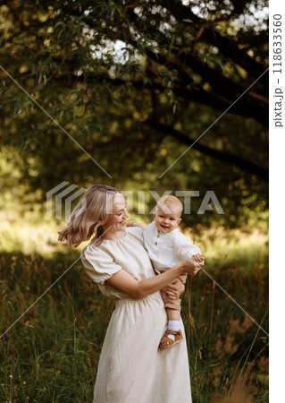 Happy woman holding a small child in her arms in the summer in a park 118633560