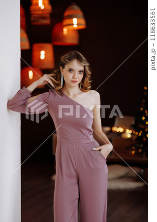 Beautiful woman in pink jumpsuit posing in Christmas interior. 118633561