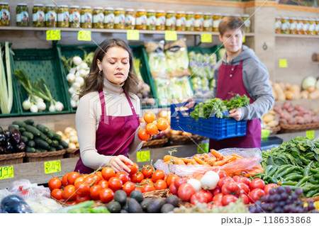 Young woman seller lays out tomatoes on counter Young woman seller lays out tomatoes on counter 118633868