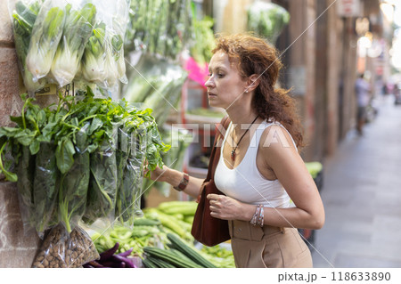 Woman choosing green vegetables at street stall in city Woman choosing green vegetables at street stall in city 118633890