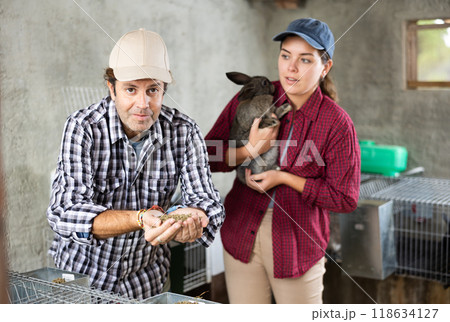 Woman and man holding rabbit and feed in their hands 118634127