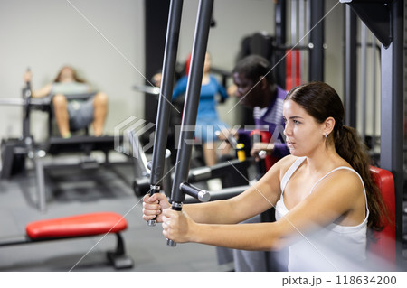 Caucasian woman doing exercises on chest fly machine in gym Caucasian woman doing exercises on chest fly machine in gym 118634200