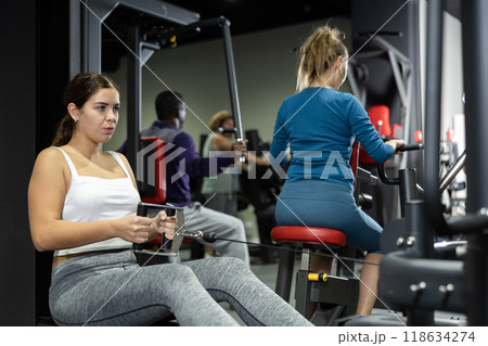 Caucasian woman doing exercises on cable row machine in gym Caucasian woman doing exercises on cable row machine in gym 118634274