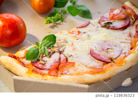 cooked pizza with salami and sausage in a box on a wooden table cooked pizza with salami and sausage in a box on a wooden table 118636323