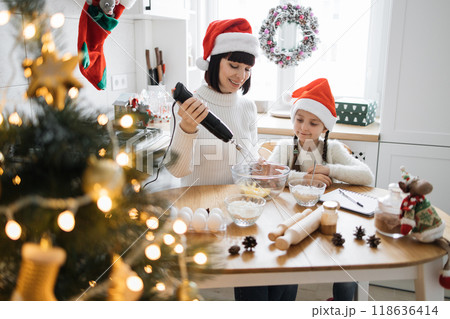 Mother and daughter baking Christmas cookies in cozy kitchen Mother and daughter baking Christmas cookies in cozy kitchen 118636414