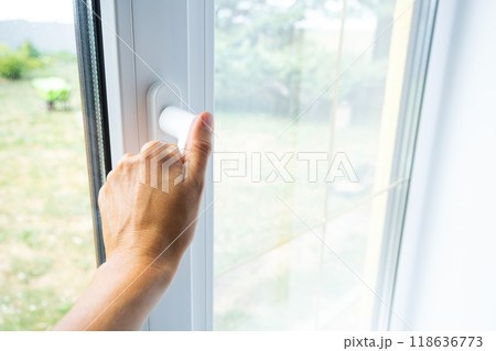 The hand holds the handle of a plastic double-glazed window, closing and opening the window with a rotary mechanism, the position of the handle for ventilation, micro-ventilation The hand holds the handle of a plastic double-glazed window, closing and opening the window with a rotary mechanism, the position of the handle for ventilation, micro-ventilation 118636773