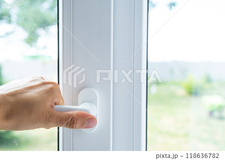 The hand holds the handle of a plastic double-glazed window, closing and opening the window with a rotary mechanism, the position of the handle for ventilation, micro-ventilation The hand holds the handle of a plastic double-glazed window, closing and opening the window with a rotary mechanism, the position of the handle for ventilation, micro-ventilation 118636782