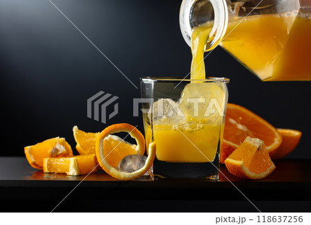Glass of orange juice with ice on a black background. Glass of orange juice with ice on a black background. 118637256