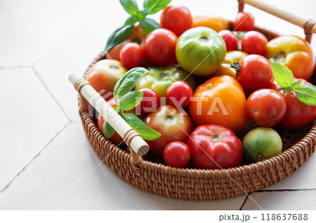 A vibrant assortment of fresh tomatoes in a woven basket on a kitchen countertop 118637688