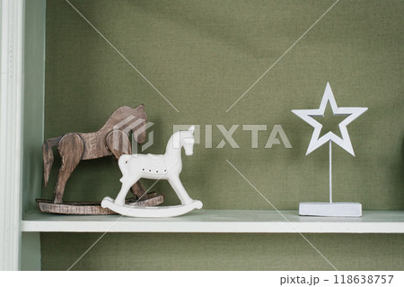 Wooden rocking horse are on a shelf against a green wall Wooden rocking horse are on a shelf against a green wall 118638757