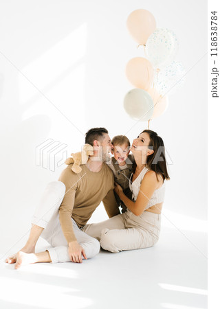 Happy young family with a young son laughing celebrating a children's birthday with balloons Happy young family with a young son laughing celebrating a children's birthday with balloons 118638784