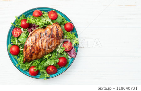 Grilled chicken breast ( fillet ) with lattuce salad and cherry tomatoes . Top view 118640731