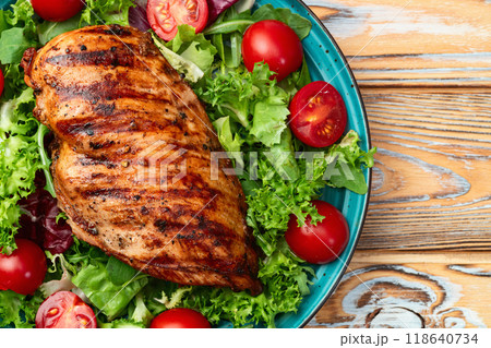 Grilled chicken breast ( fillet ) with lattuce salad and cherry tomatoes . Top view 118640734