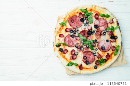 Pizza with mozzarella cheese , salami sausages , olives , and basil 118640751