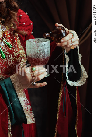 Medieval queen in red dress pouring poison into goblet Medieval queen in red dress pouring poison into goblet 118641797