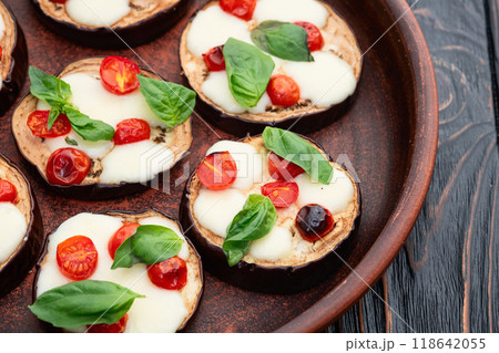 Italian mini pizza . Aubergine (eggplant ) with mozzarella cheese and basil . On rustic background Italian mini pizza . Aubergine (eggplant ) with mozzarella cheese and basil . On rustic background 118642055