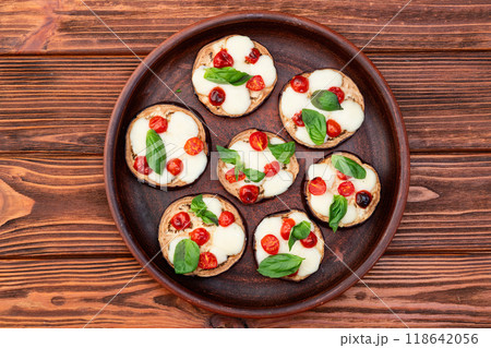 Italian mini pizza . Aubergine (eggplant ) with mozzarella cheese and basil . On rustic background Italian mini pizza . Aubergine (eggplant ) with mozzarella cheese and basil . On rustic background 118642056