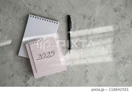 Top view of 2025 calendar, notepad and pen Top view of 2025 calendar, notepad and pen 118642581