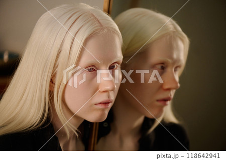Conceptual portrait of young Caucasian woman with albinism posing for camera with mirror reflection 118642941