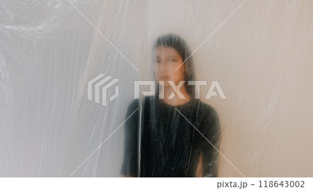 Woman aesthetic with soft blurred effect behind translucent plastic sheet showcasing artistic vision. Woman aesthetic with soft blurred effect behind translucent plastic sheet showcasing artistic vision. 118643002