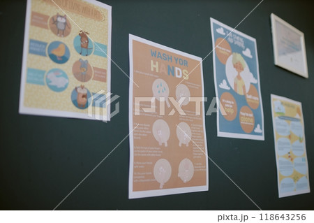 Various educational posters are displayed on the wall, featuring detailed instructions and graphics for proper hand-washing procedures and hygiene tips 118643256