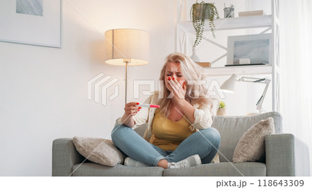 Unplanned pregnancy. Desperate woman. Sad emotion. Upset crying lady looking test result sitting sofa light room interior. Unplanned pregnancy. Desperate woman. Sad emotion. Upset crying lady looking test result sitting sofa light room interior. 118643309