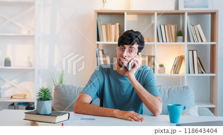 Mobile negotiation. Business call. Remote communication. Confident serious smart man speaking on phone at modern home office interior with free space. 118643404