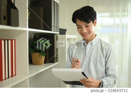 Handsome male account manager checking reports at his office desk Handsome male account manager checking reports at his office desk 118643711