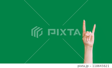 Punk gesture. Rock fan. Heavy metal greeting. Female hand showing support fingers horn sign isolated on green empty space background. 118643821
