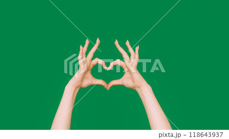 Love sign. Sympathy gesture. Romantic feeling. Female hands showing finger heart shape isolated on green empty space background. 118643937